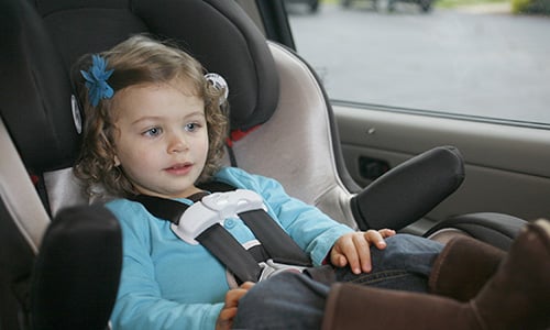 Small girl child in a car seat wearing a blue shirt