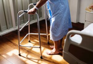 Medical patient standing in hospital room wearing gown using a walker