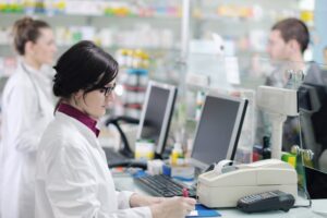 Young pharmacist in pharmacy filling medications