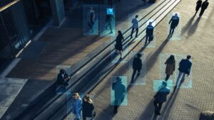 People walking through an urban plaza with digital facial recognition overlays identifying individuals using AI technology for digital evidence.