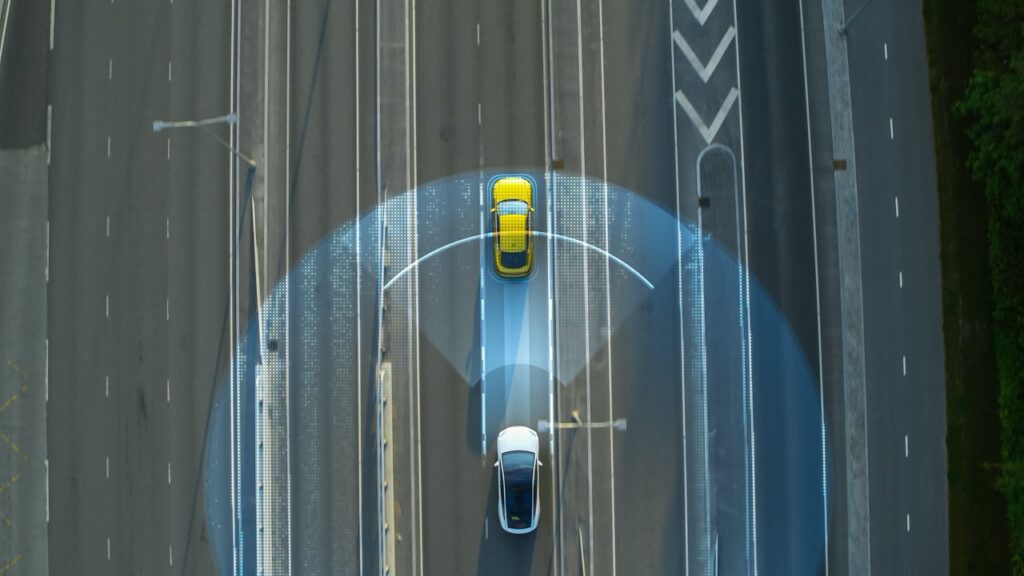 Top-down view of a vehicle’s collision detection system activating on a highway, illustrating product liability issues in automotive safety technology.