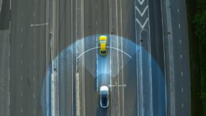 Top-down view of a vehicle’s collision detection system activating on a highway, illustrating product liability issues in automotive safety technology.